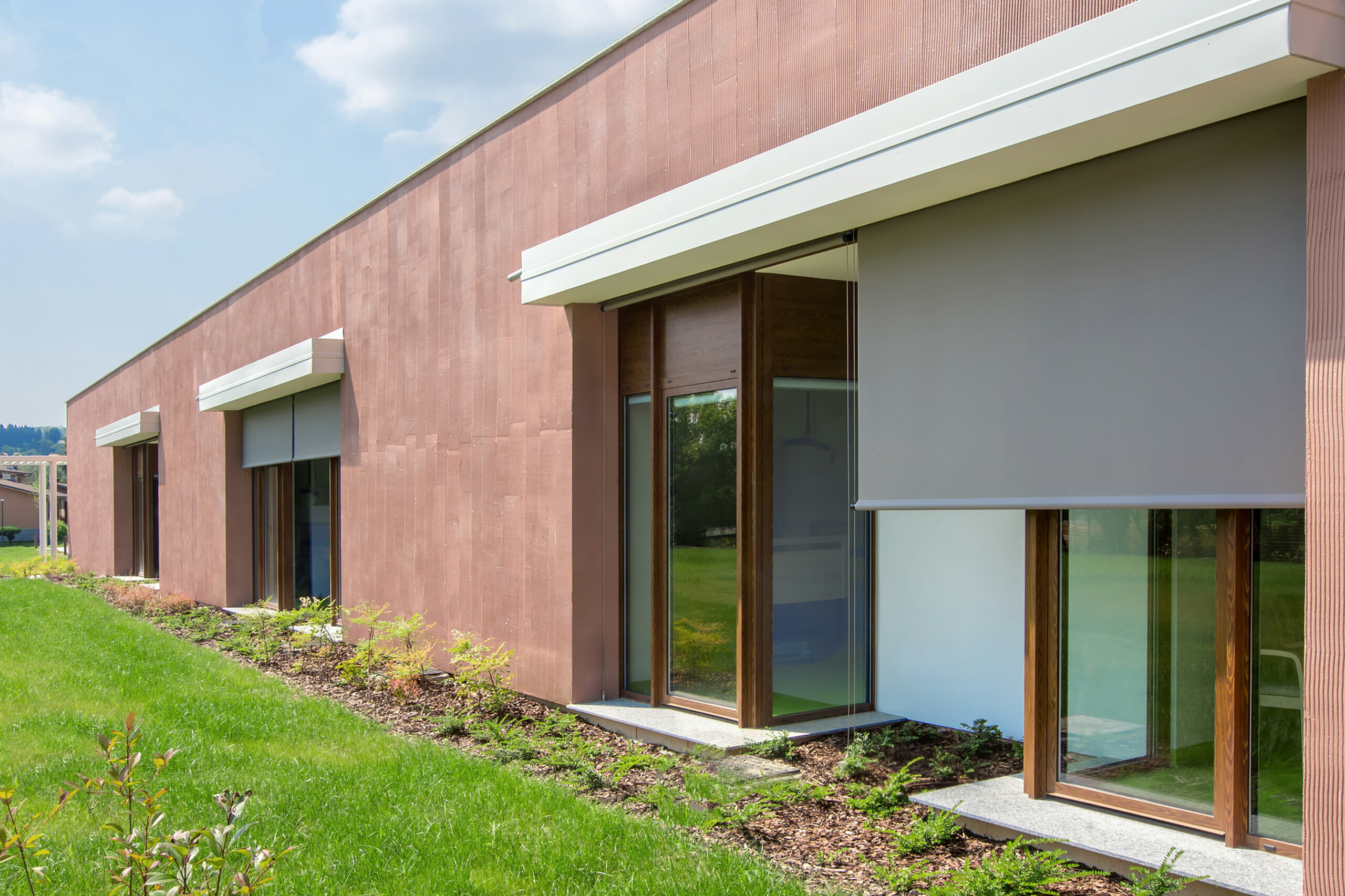 Dettaglio delle tende a rullo esterne motorizzate con guide in acciaio inox montate sulla facciata della Casa dei Ragazzi